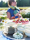Strawberry tart and teacups on a garden table