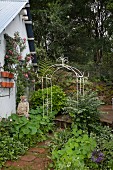 Ornate metal trellis arch over garden path next to cottage