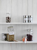 Jars of legumes and tins of preserves on a kitchen shelf