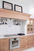 Pale wooden kitchen counter with wooden, profiled mantel hood above cooker