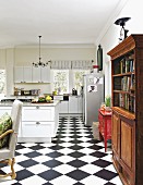 Offene Küche mit Schachbrettboden, ländlicher Einrichtung und altem Bücherschrank