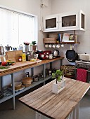 Simple wooden table opposite industrial-style kitchen counter below window