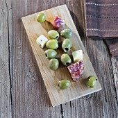 Green olives, diced provolone and salami pieces on a wooden board