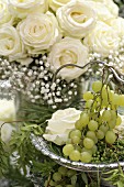 Strauss aus weißen Rosen und Schleierkraut, im Vordergrund Etagere mit weißen Weintrauben