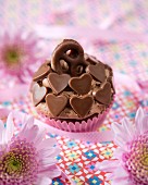 A chocolate cupcake decorated with chocolate hearts