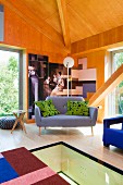 Designer sofa in corner of wood-panelled room with glass floor