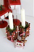 Festive, glass candle holders decorated with cinnamon sticks, ornamental toadstools and moss