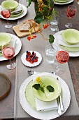 A table laid in a garden with white and pastel green crockery