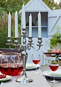A candle holder with LED candles and a punch bowl on a table laid in a garden