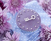 A purple cupcake decorated with a key