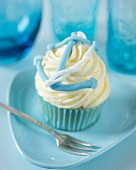 A vanilla butter cream cupcake decorated with maritime fondant (an anchor and a rope)