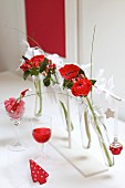 Christmas table arrangement of red flowers in test tubes in white frame