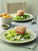 Monk fish tournedos in bacon with basil oil on green bean seeds and lettuce strips