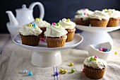 Carrots cupcakes decorated with frosting and colourful sugar pearls