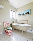 Antikes WC mit Verzierungen neben freistehender Vintage Badewanne auf weiss lackierten Dielenboden, in hellgrau getöntem Bad