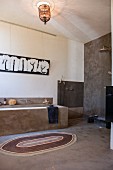 Badezimmer im Ethnostil mit grau verputzten Wänden, gemauerter Badewanne und offener Dusche