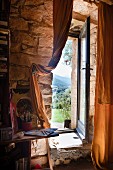 Zimmer mit Natursteinwand und Fenstertür, Blick in Berglandschaft