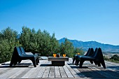 Moderne Sitzgruppe auf einer mit Holzplanken ausgelegte Terrasse umgeben von Olivenbäumen und traumhafter Aussicht