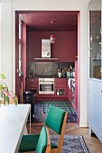 Dining area in front of open doorway leading to dusky-pink kitchen