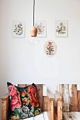 Nostalgisches Kissen auf Sessel aus Recycling-Holz mit abblätternder Farbe, vor Wand mit aufgehängten Bildern