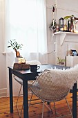 White fur blanket on retro chair at small black table below window