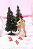 Christmas arrangement of miniature fir trees, deer figurine and stockings in artificial snow