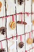 Grid of twigs decorated with pine cones, citrus slices, cinnamon sticks and stags