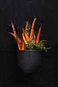 Caramelized carrots with thyme in a black bowl