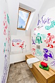 Modernes Bad unter dem Dach, mit verschiedenfarbigen Comiczeichnungen an Wand