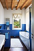 Long, modern bathroom with blue mosaic tiles and wood-beamed ceiling