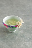 A tea bowl of elderflower tea decorated with rubber bands