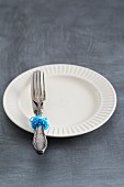 Silver cutlery decorated with rubber bands on a plate