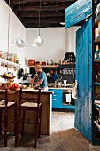 Counter and bar stools in kitchen next to blue-painted cupboard; man in background