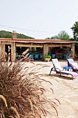 Finca terrace with roofed dining area, two loungers and grasses in foreground