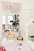 Rocking horse in white, child's bedroom with view into living room