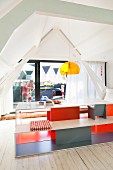 Designer Tisch und Bankgarnitur innenseitig farbig gestrichen vor Glasfront in Giebelwand, Blick auf Familie auf Dachterrasse