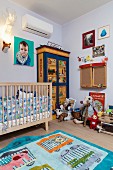 Rug with animal motifs, cot and soft toys on painted wardrobe in cheerful, bright child's bedroom
