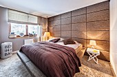 Bedroom with long-pile carpet and fabric-covered panelled wall; double bed with upholstered frame