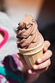 A girl holding a chocolate ice cream cone