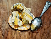 A cracker topped with blue cheese and honey