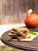 Slices of pumpkin seed bread, stacked, on a rustic garden table