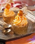 Cupcakes decorated with orange butter cream and physalis