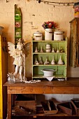 Engelfigur und kleiner Regalschrank, grün lackiert, mit Trichter Sammlung, auf Holztisch