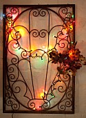 Wrought iron lattice decorated with flowers and fairy lights hung on wall