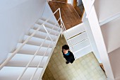 View down white steel staircase to woman standing in stairwell