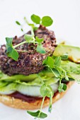 A burger with pea shoots, avocado, lettuce, onions and ketchup