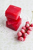 A stack of redcurrant sorbet cubes with a frozen sprig of redcurrants