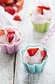 Frozen strawberry yoghurt in coloured bowls with coloured spoons