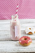 A bottle of strawberry milk with yoghurt spots and mini iced doughnuts