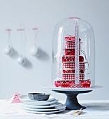 Stack of gifts wrapped in red and white under glass cover with numbers written on tape